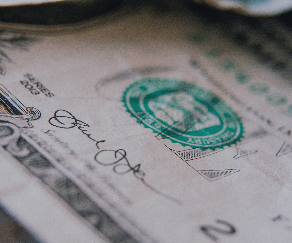 Close-up detail of a United States two-dollar bill showing the green Treasury seal and part of the signature.